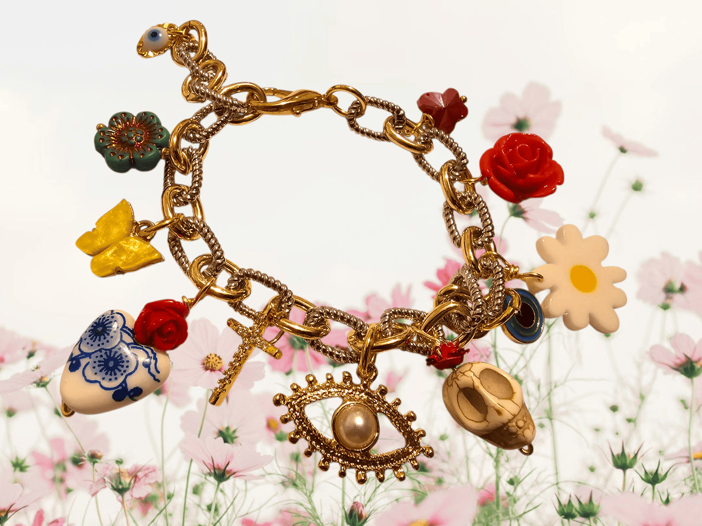Gold charm bracelet with various charms against a floral background